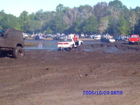 1987 Suzuki Samurai - Multiple vehicles are stuck in a muddy field during an event.