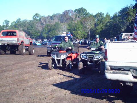 1987 Suzuki Samurai - ATVs and a lifted pickup truck are seen on a dirt track with trees in the background.