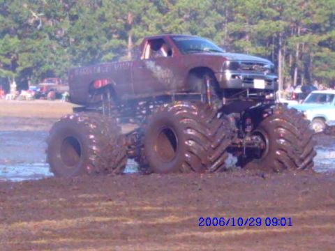 1987 Suzuki Samurai - A monster truck is stuck in the mud during a bogging event, with other vehicles visible in the background.