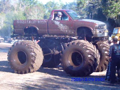 1987 Suzuki Samurai - A heavily modified truck with oversized tires sits on display, with spectators nearby.