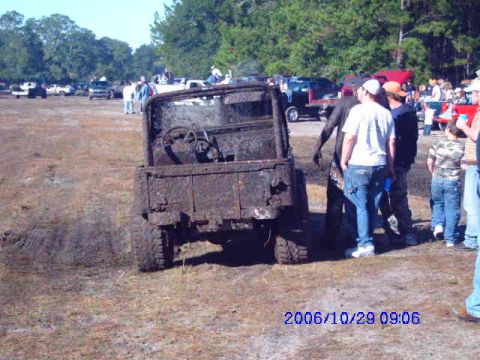 1987 Suzuki Samurai - A heavily muddied 1987 Suzuki Samurai is seen from the rear at an outdoor event with spectators.
