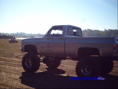 1987 Suzuki Samurai - This lifted pickup truck features blue flame decals and large off-road tires.