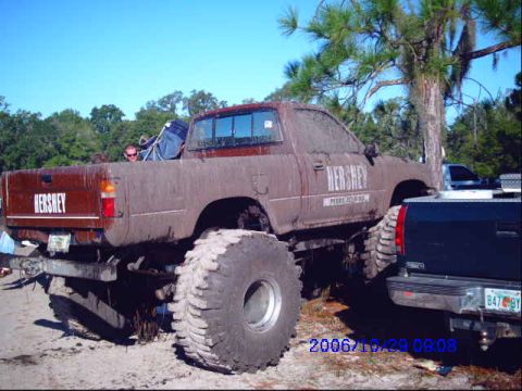 1987 Suzuki Samurai - This heavily modified pickup truck is covered in mud and features oversized tires, suggesting it's used for off-road activities.