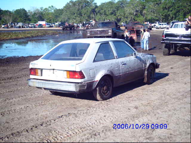 White coupe with mud splatters, rear 3/4 view