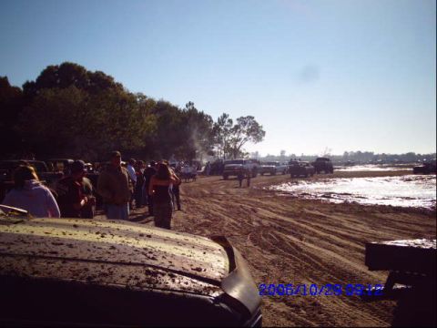 1987 Suzuki Samurai - A crowd gathers in a muddy field with several vehicles present, suggesting an outdoor event or off-road activity.