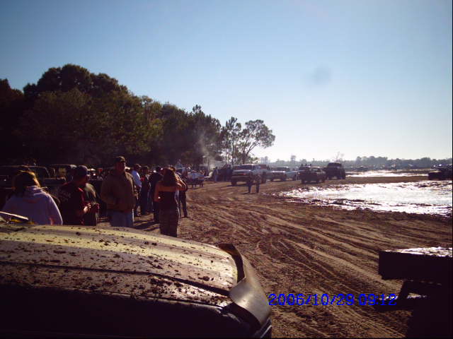 Muddy field with people and vehicles under a clear blue sky