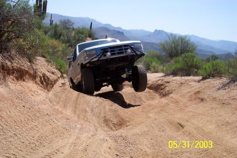 1993 Ford Bronco - Ford Bronco navigates a rough off-road trail in a desert landscape.
