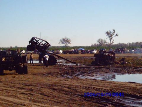 1987 Suzuki Samurai - Off-road vehicles participating in a mud bogging event, with one vehicle overturned in the mud.