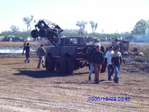 1987 Suzuki Samurai - A modified truck with a buggy on its roof is the center of attention at an outdoor event.