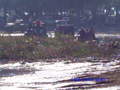 1987 Suzuki Samurai - Off-road vehicles navigate a muddy field with vegetation and debris scattered around.