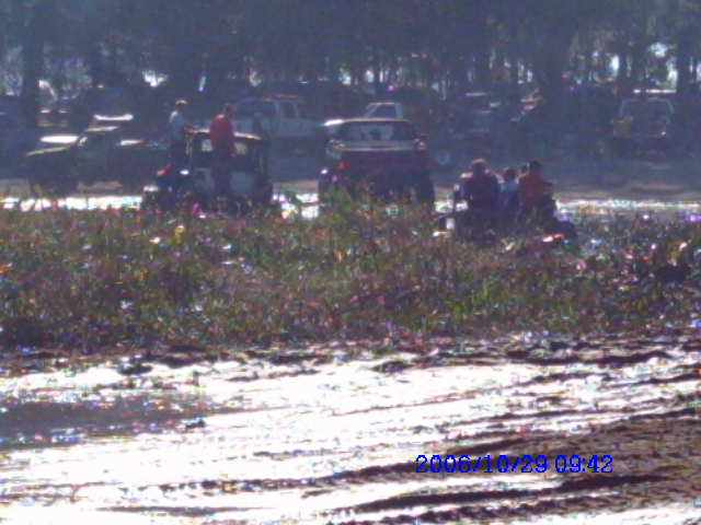 Several off-road vehicles with people riding in them are in a muddy, grassy field. Date stamp reads 2006/10/29 09:42