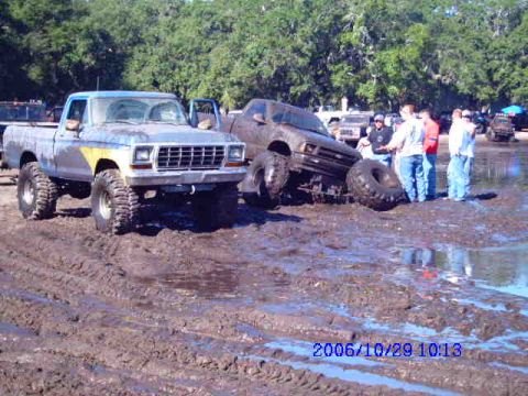 1987 Suzuki Samurai - Two trucks are stuck in deep mud with several people observing the scene.