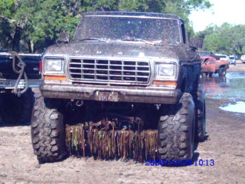 1987 Suzuki Samurai - A heavily muddied 1979 Ford F-Series truck sits in a muddy field with other vehicles in the background.