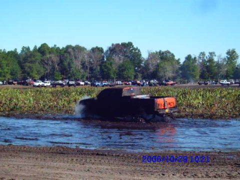 1987 Suzuki Samurai - A truck is stuck in the mud, with other vehicles visible in the background.