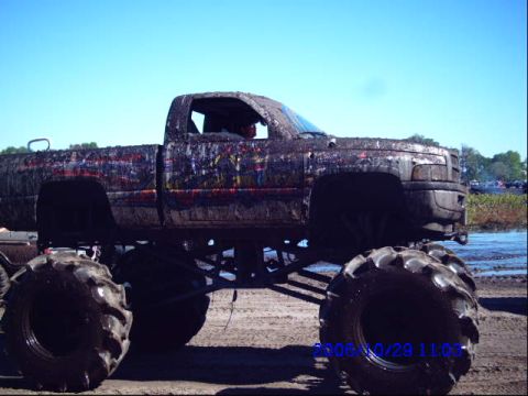 1987 Suzuki Samurai - This heavily modified truck is caked in mud, suggesting it has been used for off-roading or a mud bog event.