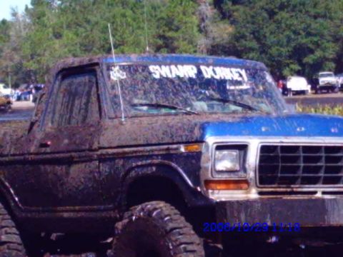 1987 Suzuki Samurai - This heavily muddied truck, likely from the early 1980s, is seen in a 3/4 front view.