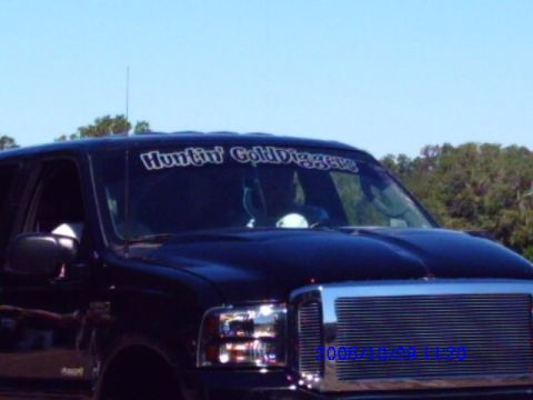 1987 Suzuki Samurai - A dark SUV is seen from the front, with a banner on the windshield reading "Huntin' Gold Diggers".