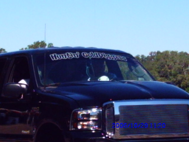 Dark SUV front view with "Huntin' Gold Diggers" windshield banner