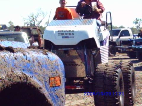 1987 Suzuki Samurai - Muddy off-road vehicles are gathered at an outdoor event, with one vehicle displaying text on its rear panel.