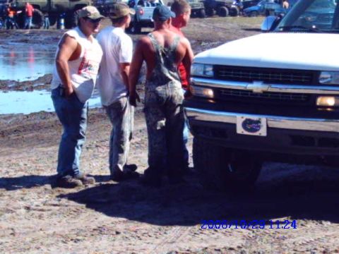 1987 Suzuki Samurai - A Chevrolet pickup truck is parked in a muddy area with several people standing nearby.