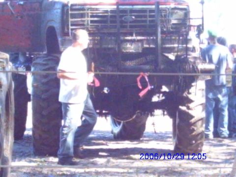 1987 Suzuki Samurai - A monster truck is viewed from the front, with a man standing beside it.