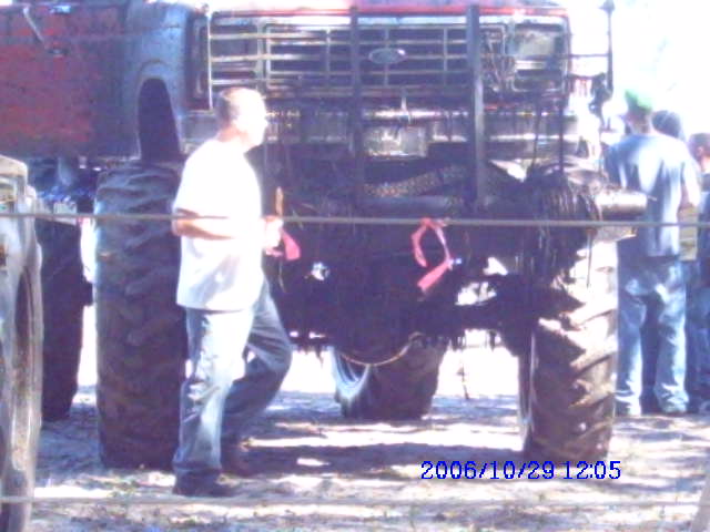 Monster truck with large tires and a man in a white shirt standing next to it