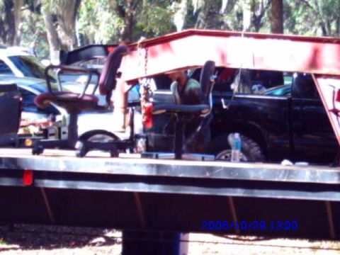 1987 Suzuki Samurai - Office chairs are being transported on a flatbed trailer, with a pickup truck and car in the background.
