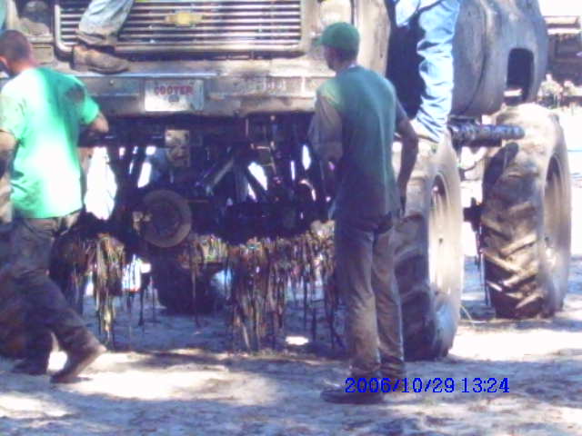 Tractor rear view with hanging debris, two people visible
