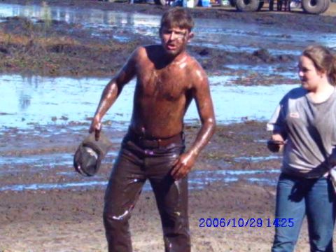 1987 Suzuki Samurai - Two people covered in mud stand in a muddy field with a vehicle partially visible in the background.