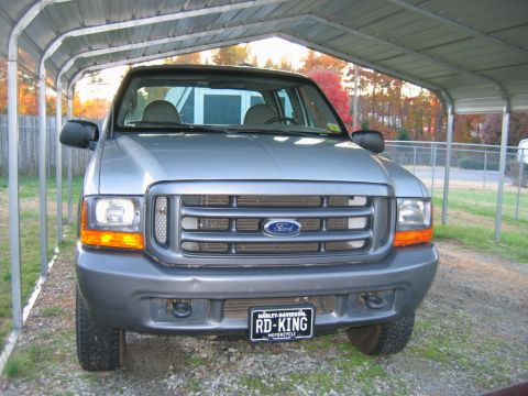 1992 Ford Mustang - This Ford truck, likely from the late 1990s, is parked under a carport with autumn foliage visible in the background.