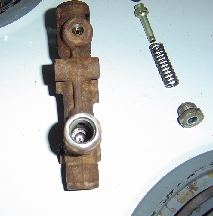 Rusted brake master cylinder component with spring and bolt nearby