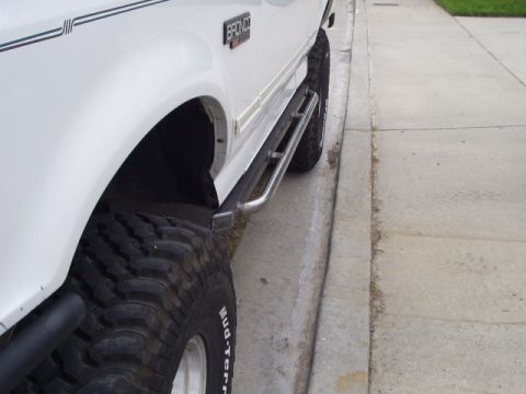 1993 Ford Bronco - Close-up of a 1993 Ford Bronco's side, highlighting the rock slider and large tire.