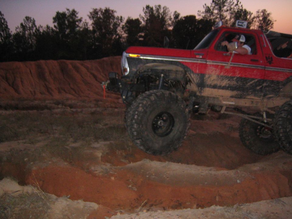 Red off-road SUV with large tires driving on dirt terrain