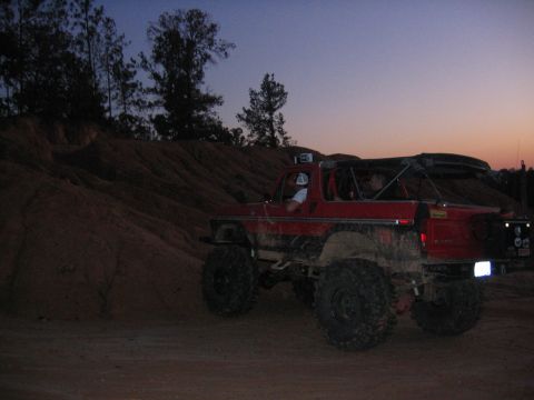 1979 Ford Bronco - Off-road SUV with custom modifications driving on a dirt hill during twilight.