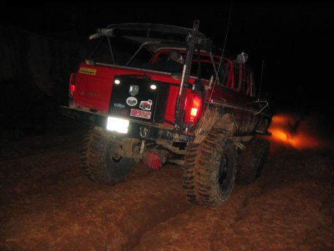 1979 Ford Bronco - This heavily modified SUV is navigating a muddy trail in the dark, with flames erupting from its exhaust.