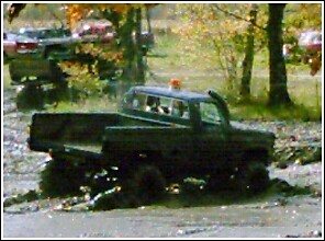1976 Chevrolet Silverado 2500 - Modified pickup truck navigates a muddy terrain, with another vehicle in the background.