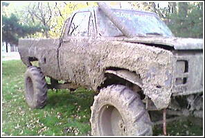 1976 Chevrolet Silverado 2500 - This heavily mud-caked pickup truck features a snorkel intake and oversized tires, suggesting it's prepared for off-road use.