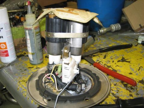 1979 Ford Bronco - A disassembled fuel pump assembly sits on a workbench, surrounded by tools and cleaning supplies.