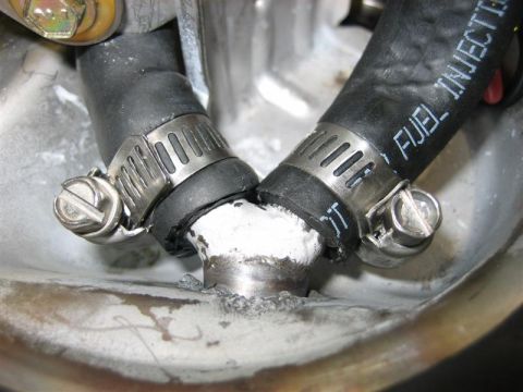1979 Ford Bronco - A close-up view shows a fuel injection hose connected to a metal fitting with hose clamps.
