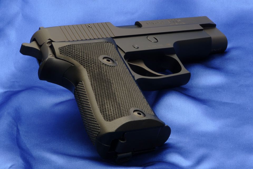 Black semi-automatic pistol with textured grip, resting on a blue cloth