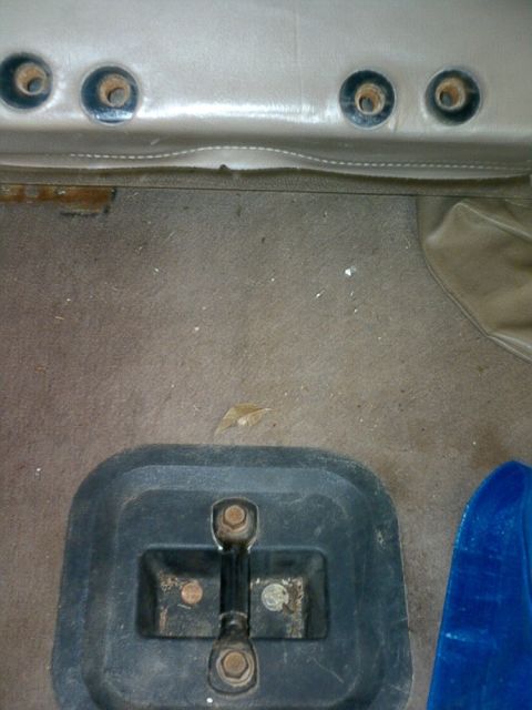 1995 Ford Bronco - Close-up of the interior of a vehicle, focusing on the seatbelt anchor points and a floor-mounted latch.