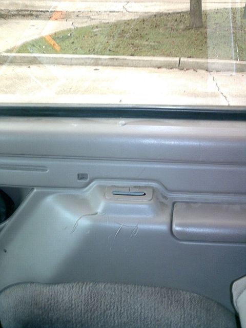 1995 Ford Bronco - Interior view of a vehicle's door panel, showing wear and tear on the gray plastic surface.