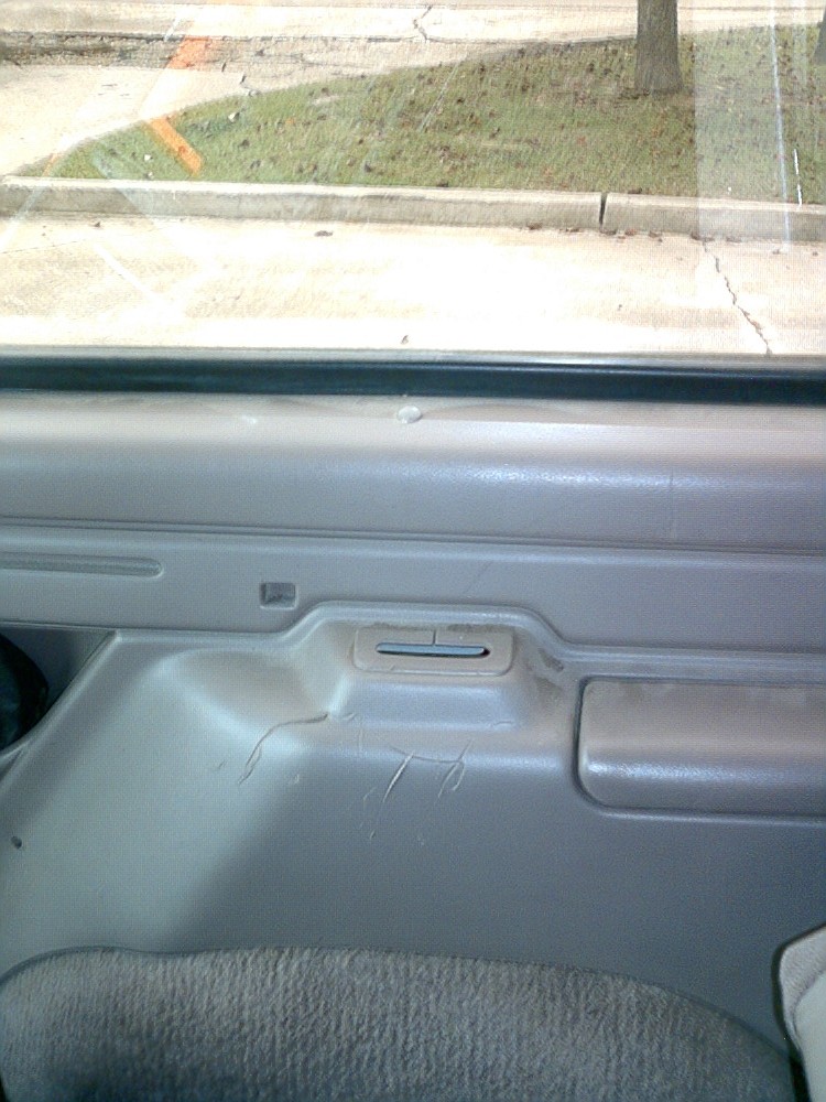 Gray interior door panel with visible scratches and a carpeted lower section