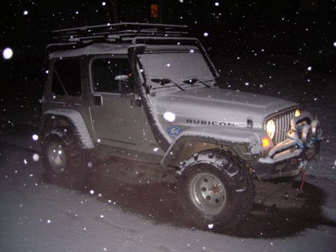 2003 Jeep TJ - A silver 2003 Jeep Wrangler TJ is seen driving in the snow at night, equipped with a snorkel and roof rack.