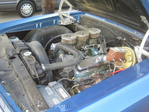 1968 Ford Mustang - Close-up of a car's engine compartment, a V8 engine with multiple carburetors and a prominent battery.