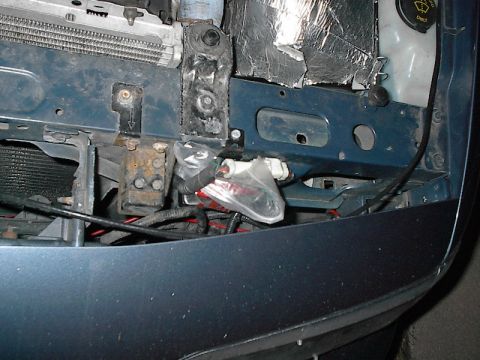 1985 Mercury Grand Marquis - Close-up view of the front end of a vehicle, revealing exposed wiring, radiator, and bumper structure.