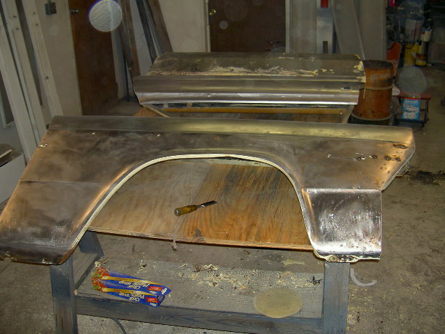 Bare metal car fender and door panel on a workbench