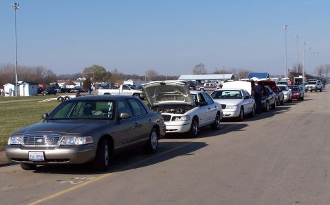 2000 Ford Crown Victoria - A line of Ford Crown Victorias are parked on an asphalt surface under a clear blue sky.