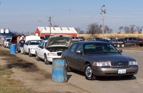 2000 Ford Crown Victoria - Several Ford Crown Victorias are parked in a line, with some hoods open, under a clear sky.