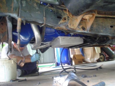 1984 Ford Bronco - A person works on the undercarriage of a vehicle, which has been painted blue.